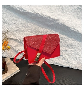 Detail of red sequined flap on a leather crossbody bag with a gold metal lock