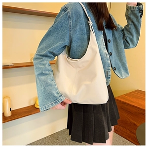 Chic cream white hobo shoulder bag styled with a denim jacket and black pleated skirt