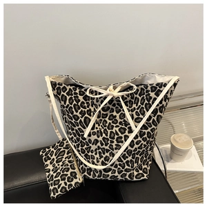 Detail of leopard print tote bag set with matching small pouch on a stylish leather chair