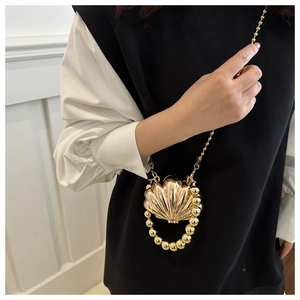 Detailed view of a mini golden shell-shaped evening bag with beaded handle and chain strap