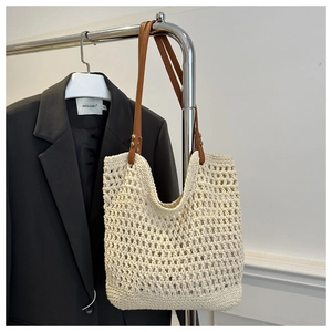 Detail of hollow woven tote bag featuring brown leather straps and rivet hardware