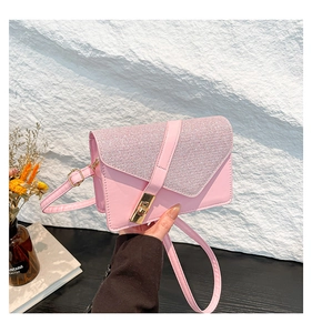 Detail of pink sequin shoulder bag with golden rectangular clasp held by hand