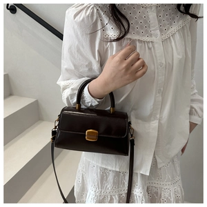 Brown vintage leather square handbag shown worn as a crossbody bag on white stairs