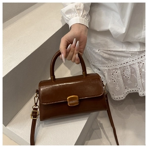 Detail of vintage dark brown faux leather bag with golden square clasp and curved handle
