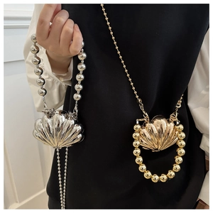 Detail of shell-shaped metallic handbags in gold and silver with large pearl handles