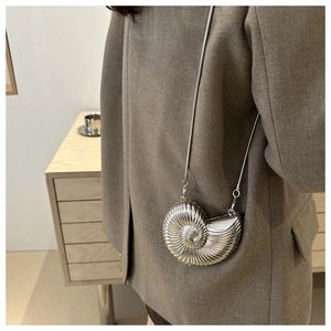 Close-up of a silver snail-shaped hardshell clutch bag with detailed spiral metallic texture