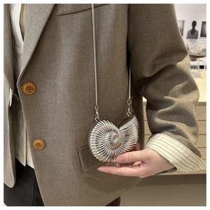 Detailed view of a silver seashell mini crossbody bag with metallic spiral texture and chain