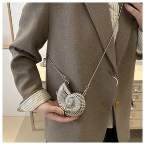 Detail of silver nautilus-shaped mini bag with metallic finish and delicate chain strap