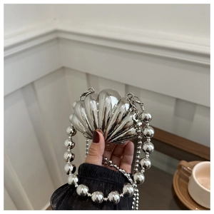 Detail of silver shell-shaped evening bag with metallic finish and sphere chain handle