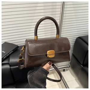 Detail view of vintage dark brown faux leather handbag with gold metal clasp and top handle