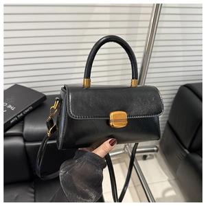 Detail of black vintage leather handbag featuring a square golden metal buckle closure