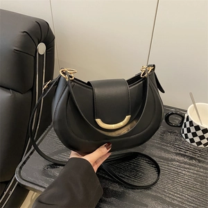 Minimalist black crescent shoulder bag with a gold metal clasp and premium matte finish