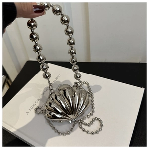 Macro view of silver shell-shaped mini bag with metallic chrome finish and pearl handle
