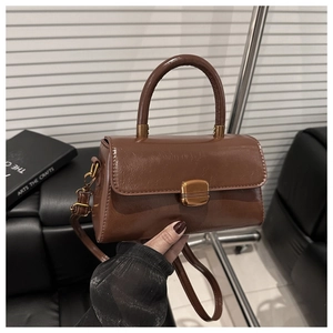 Close-up of vintage brown glossy handbag with gold clasp and adjustable strap