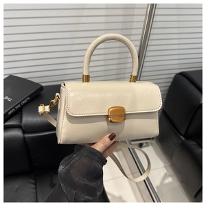 Detail of cream white leather handbag with vintage gold buckle and round top handle