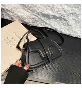 Detail of black lychee grain leather crossbody bag with elegant gold snap button closure
