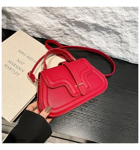 Detailed close-up of red lychee leather handbag featuring wave flap and metallic buckle
