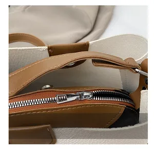 Detail showing smooth silver metal zipper on white and brown leather bucket bag