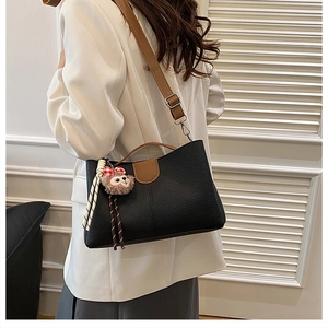 Litchi pattern black tote with brown contrast flap and plush charm on adjustable strap