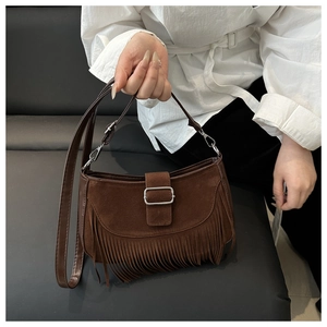 Détail du sac à franges en daim marron avec pampilles ethniques et boucle en métal argenté