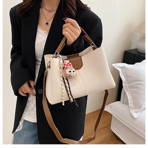 Detail of lychee pattern leather tote with adjustable strap and plush pendant decoration