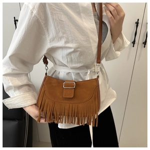 Détail d'un sac bandoulière en daim marron avec de longues franges et boucle métallique
