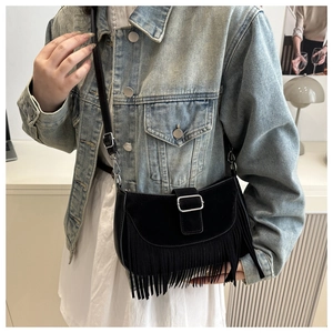 Détail d'un sac besace noir en daim avec de longues franges et une boucle métallique