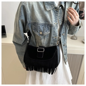 Détail du sac besace noir à franges avec boucle argentée porté sur une veste