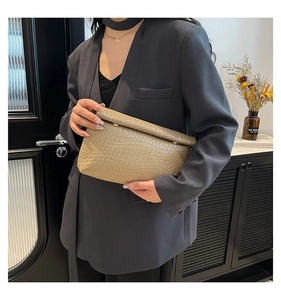 Détail de la texture cuir gaufré kaki et de la boucle dorée sur la pochette à rabat