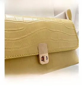 Détail du sac en cuir jaune clair à motif crocodile avec fermoir rotatif doré