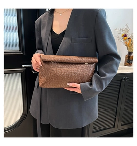 Detail showing the dark brown woven leather texture and folded edge design of the clutch bag