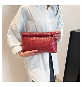 Détail d'une pochette en cuir tressé rouge avec texture Intrecciato et fermeture à rabat