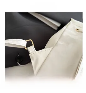 Détail macro du sac à dos en similicuir blanc avec boucles dorées et coutures soignées