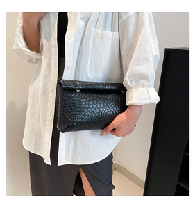 Close-up of black woven leather texture and elegant gold metal clasp on a handbag