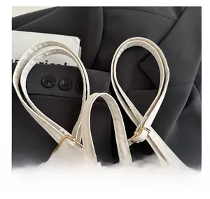 Détail de la poignée du sac à dos blanc cassé avec boucle dorée sur un blazer noir
