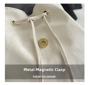 Détail de la boucle magnétique en métal et du cordon sur le sac à dos crème