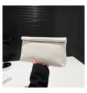 Detail of white woven texture on leather crossbody bag with gold metal hardware