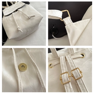 Détail du sac à dos blanc vintage en cuir texturé avec cordon de serrage et boucle dorée
