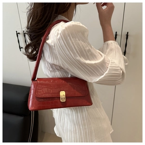 Détail du sac à bandoulière rouge motif crocodile avec une boucle dorée élégante
