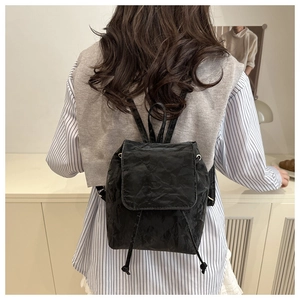 Detail of black pleated mini backpack with drawstring closure and vintage texture