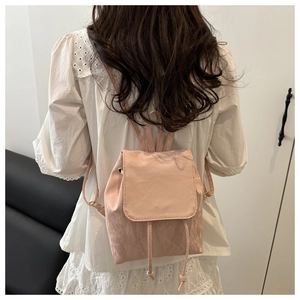 Détail d'un sac à dos rose en cuir texturé avec cordon de serrage et rabat chic