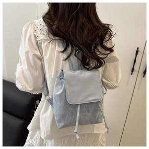 Détail arrière d'un sac à dos en nylon bleu clair avec cordon et rabat de fermeture