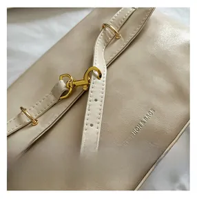 Dettaglio della borsa in pelle crema con goffratura FASHION & BAGS e ganci dorati