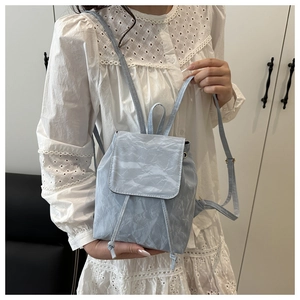 Détail du mini sac à dos bleu clair montrant le tissu imperméable et le cordon de serrage