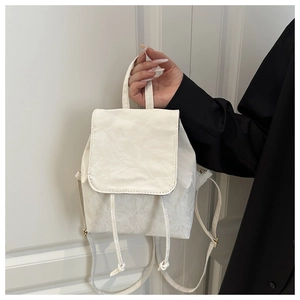 Detail of vintage textured white backpack with drawstring closure and flap cover