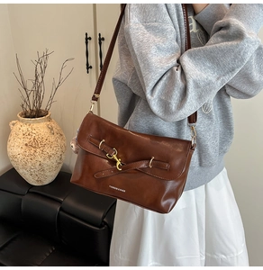 Dettaglio borsa in pelle marrone vintage con fibbia in metallo e finitura testurizzata