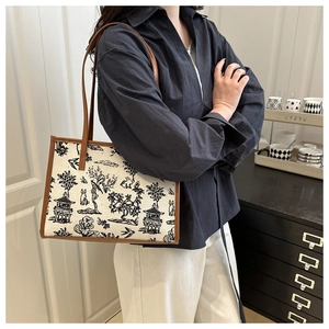 Canvas tote bag with landscape art print and brown leather straps worn by a model