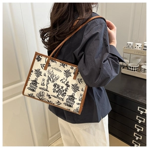 Dettaglio della grande borsa tote in tela con stampa vintage e manici in pelle marrone