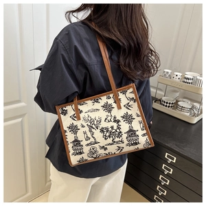 Dettaglio della borsa tote in tela vintage con motivo nero e tracolle in pelle marrone