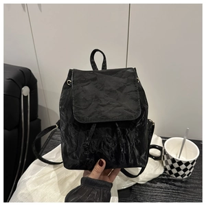 Detail view of mini black backpack with crinkled texture and sleek drawstring closure